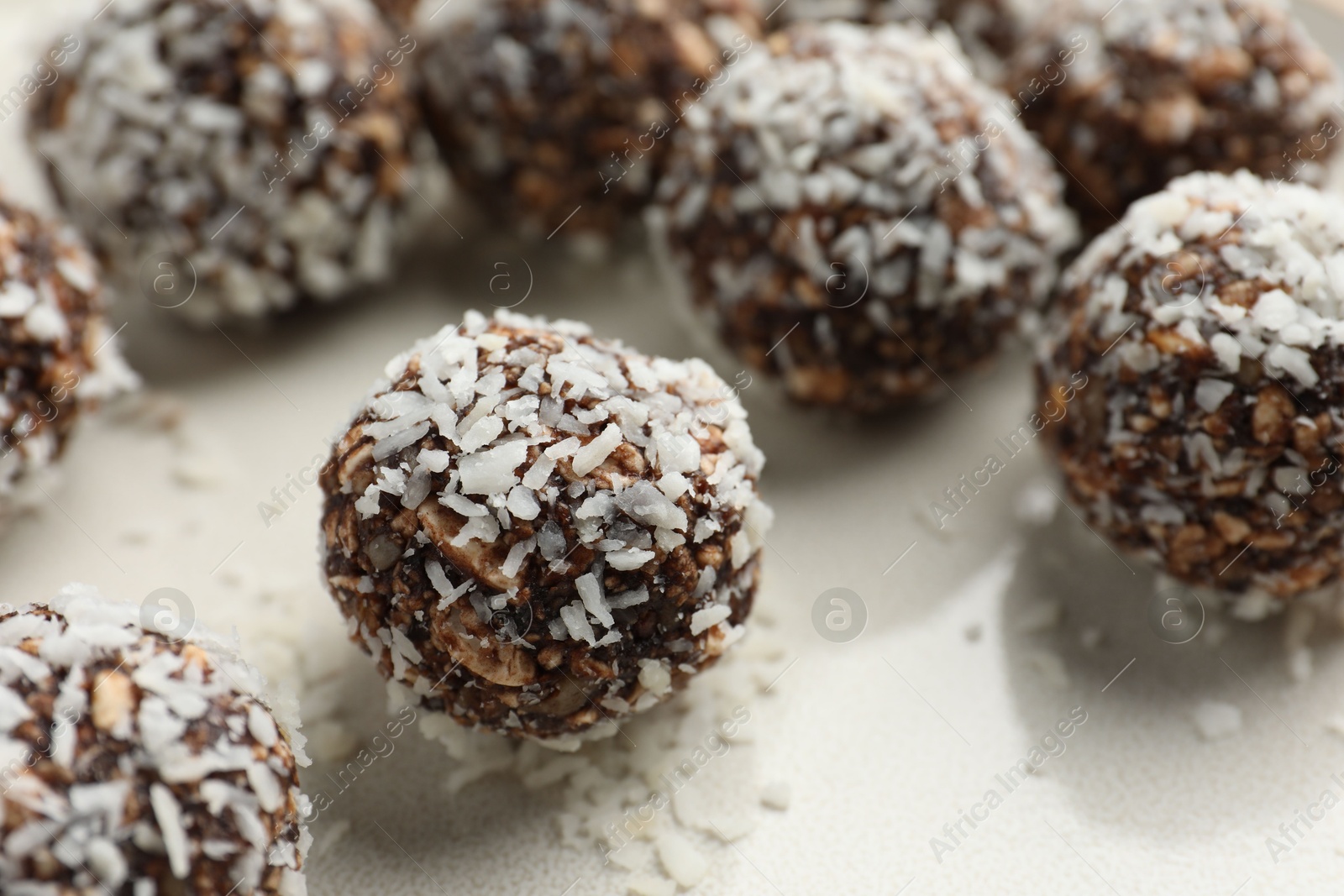 Tasty chocolate candies with nuts and coconut flakes on plate, closeup Photo of Tasty chocolate candies with nuts and coconut flakes on plate, closeup