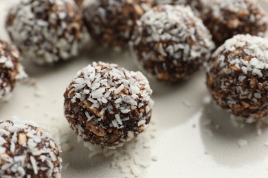 Photo of Tasty chocolate candies with nuts and coconut flakes on plate, closeup