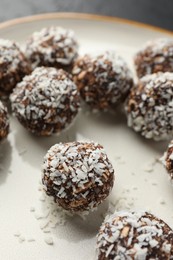 Photo of Tasty chocolate candies with nuts and coconut flakes on plate, closeup