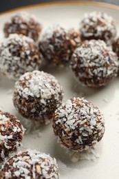Photo of Tasty chocolate candies with nuts and coconut flakes on plate, closeup