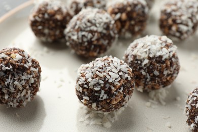Photo of Tasty chocolate candies with nuts and coconut flakes on plate, closeup