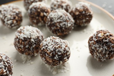 Photo of Tasty chocolate candies with nuts and coconut flakes on plate, closeup