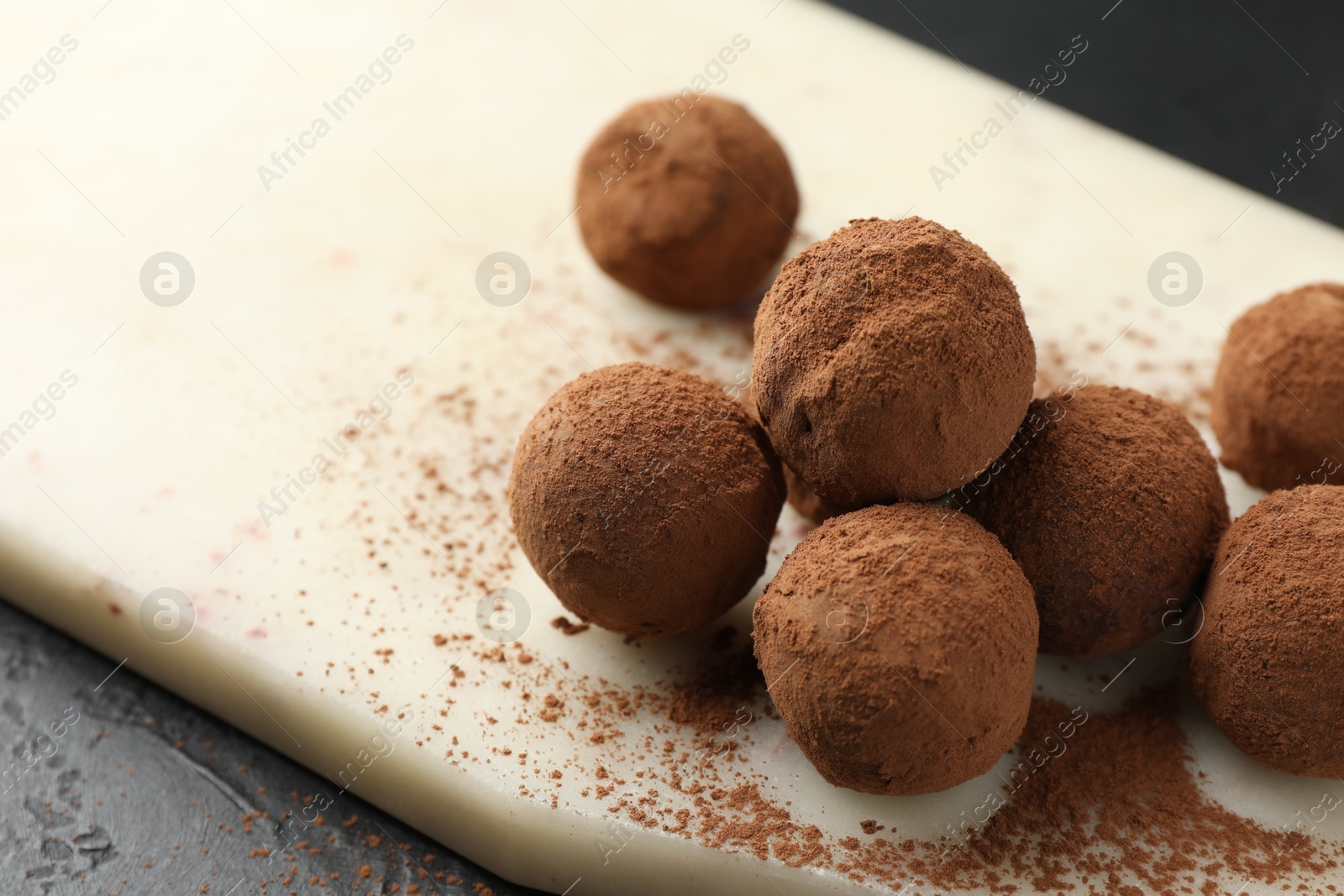 Tasty chocolate candies with cocoa powder on black table, closeup. Space for text Photo of Tasty chocolate candies with cocoa powder on black table, closeup. Space for text