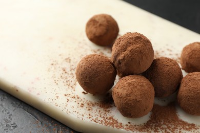 Photo of Tasty chocolate candies with cocoa powder on black table, closeup. Space for text