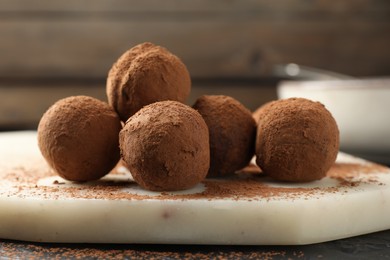 Photo of Tasty chocolate candies with cocoa powder on table, closeup