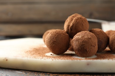 Photo of Tasty chocolate candies with cocoa powder on table, closeup. Space for text