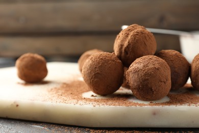 Photo of Tasty chocolate candies with cocoa powder on table, closeup