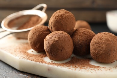 Photo of Tasty chocolate candies with cocoa powder on table, closeup