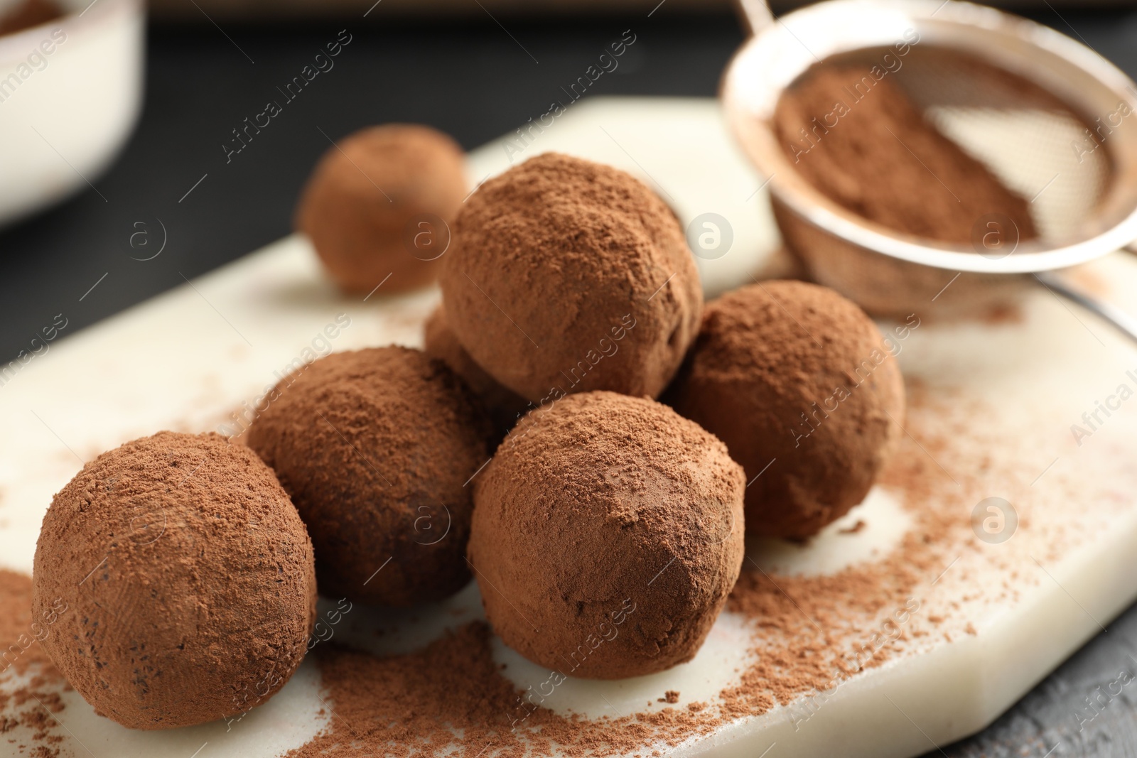 Tasty chocolate candies with cocoa powder on table, closeup Photo of Tasty chocolate candies with cocoa powder on table, closeup