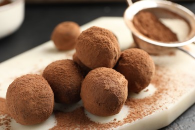 Photo of Tasty chocolate candies with cocoa powder on table, closeup