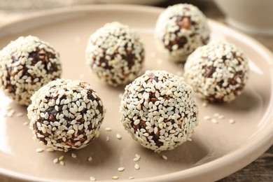 Photo of Tasty chocolate candies with nuts and sesame seeds on table, closeup
