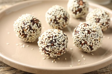 Photo of Tasty chocolate candies with nuts and sesame seeds on table, closeup