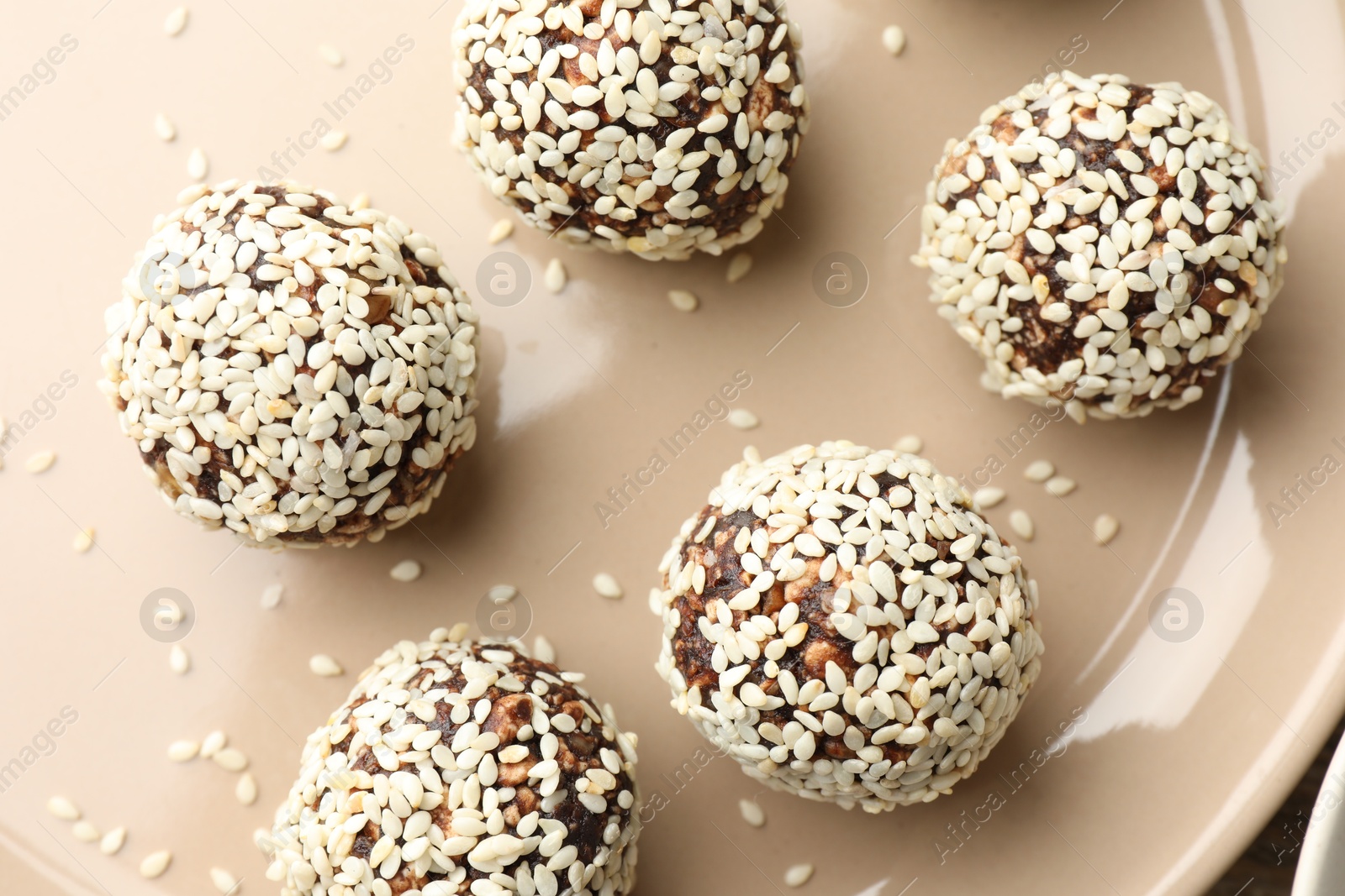Tasty chocolate candies with nuts and sesame seeds on plate, top view Photo of Tasty chocolate candies with nuts and sesame seeds on plate, top view