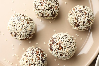 Photo of Tasty chocolate candies with nuts and sesame seeds on plate, top view
