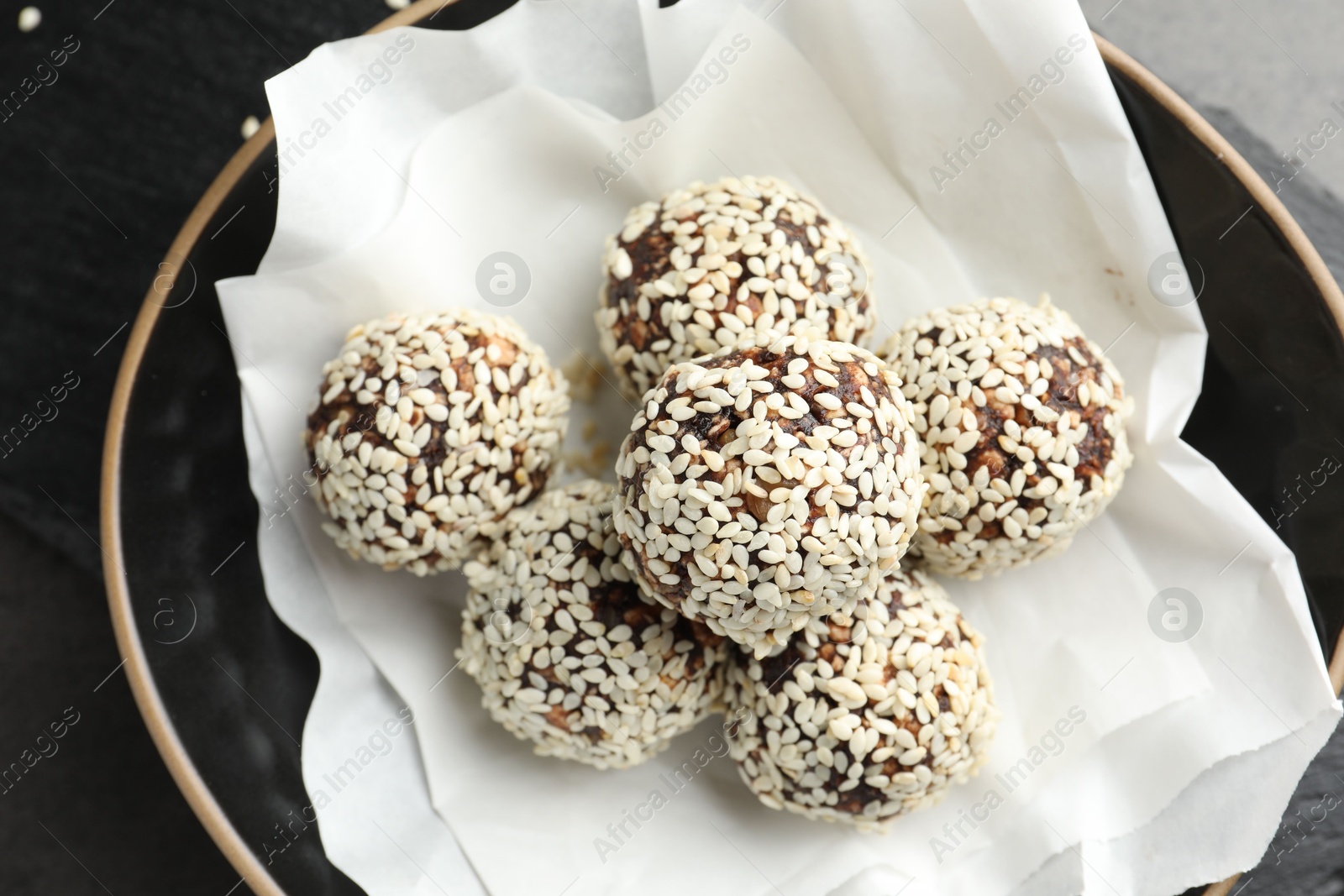 Tasty chocolate candies with nuts and sesame seeds in bowl on table, above view Photo of Tasty chocolate candies with nuts and sesame seeds in bowl on table, above view