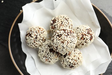 Photo of Tasty chocolate candies with nuts and sesame seeds in bowl on table, above view