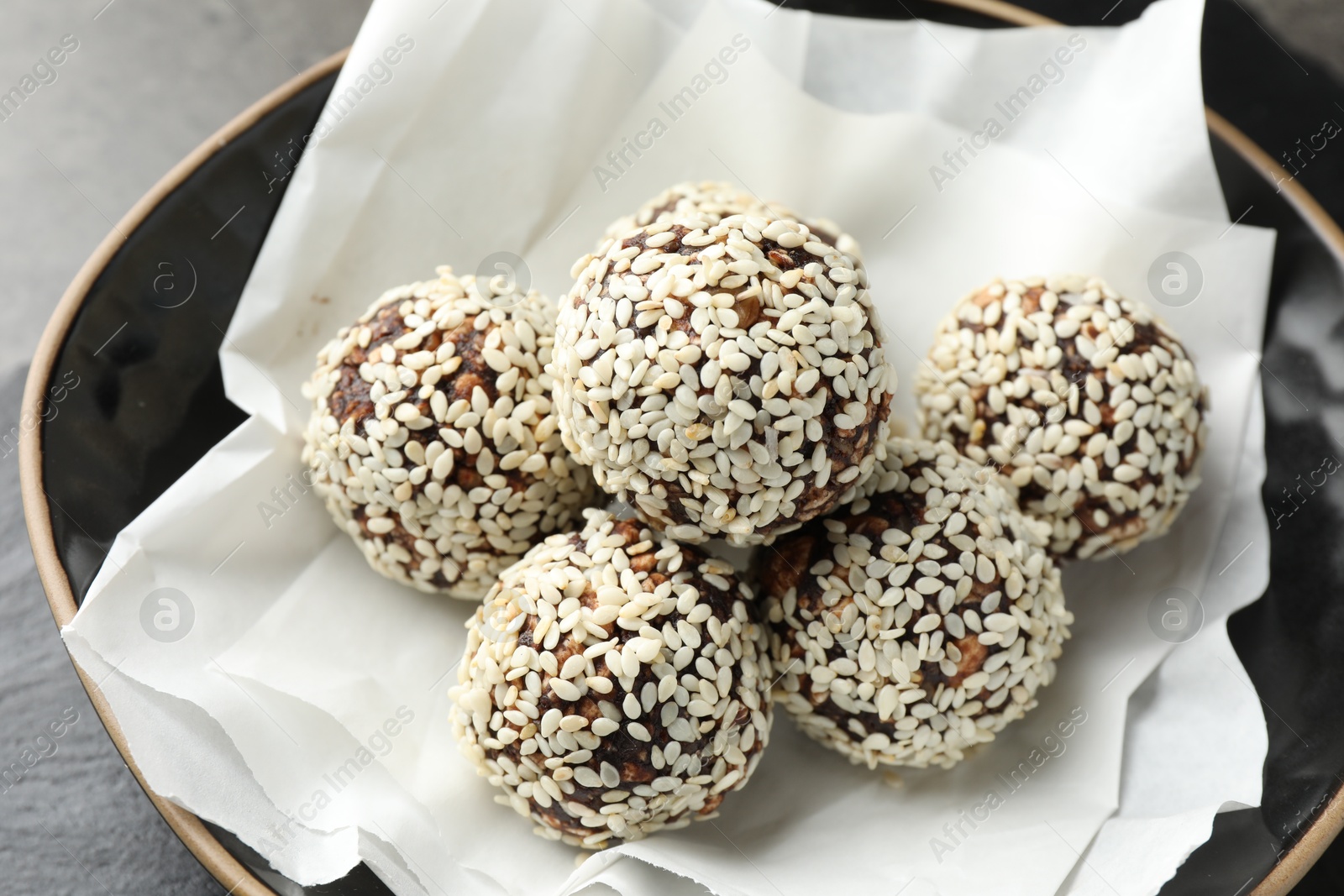 Tasty chocolate candies with nuts and sesame seeds in bowl on table, closeup Photo of Tasty chocolate candies with nuts and sesame seeds in bowl on table, closeup