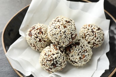 Photo of Tasty chocolate candies with nuts and sesame seeds in bowl on table, closeup