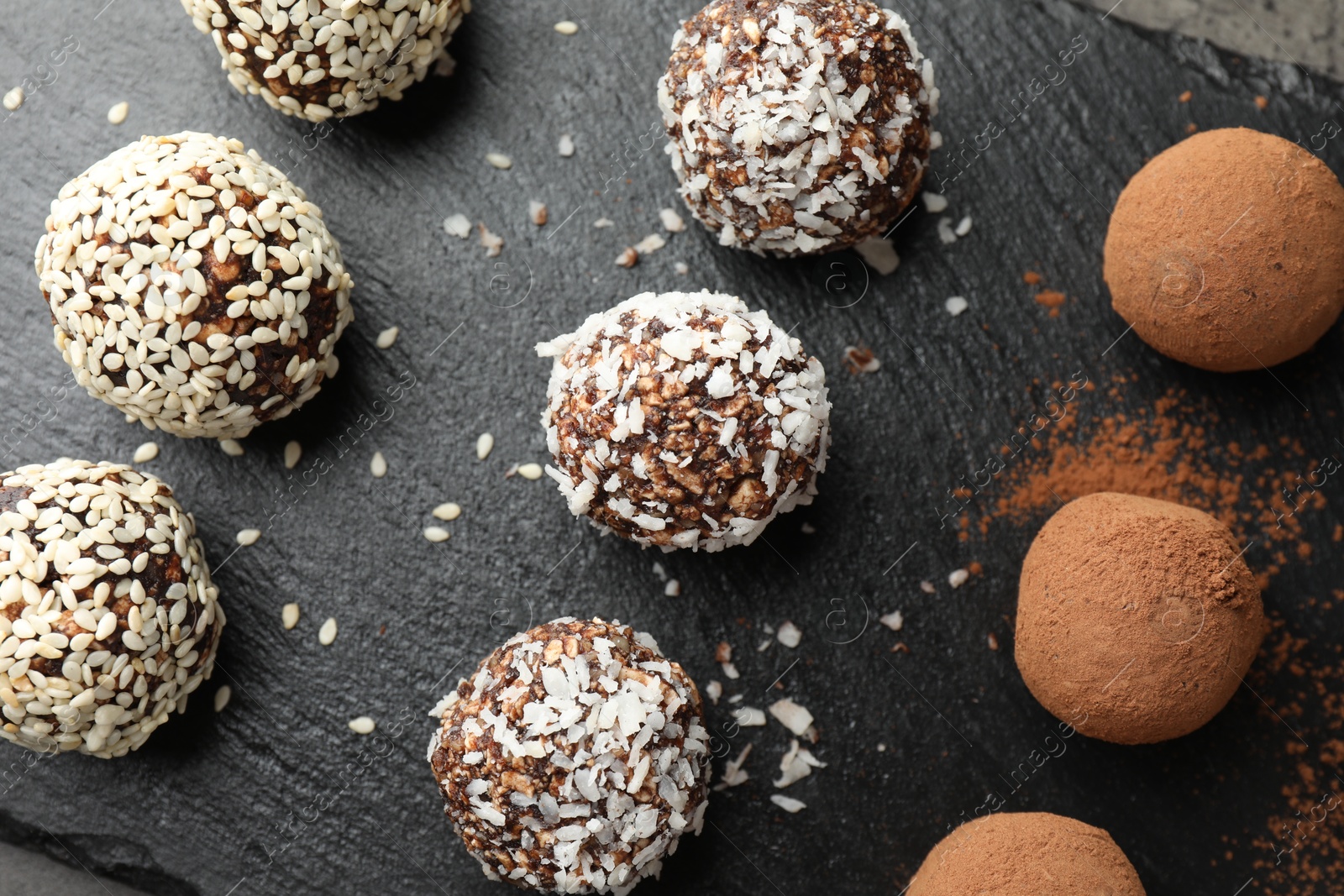 Tasty chocolate candies with cocoa powder, nuts, coconut flakes and sesame seeds on table, top view Photo of Tasty chocolate candies with cocoa powder, nuts, coconut flakes and sesame seeds on table, top view
