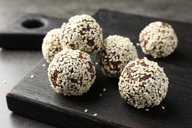 Photo of Tasty chocolate candies with nuts and sesame seeds on grey table, closeup