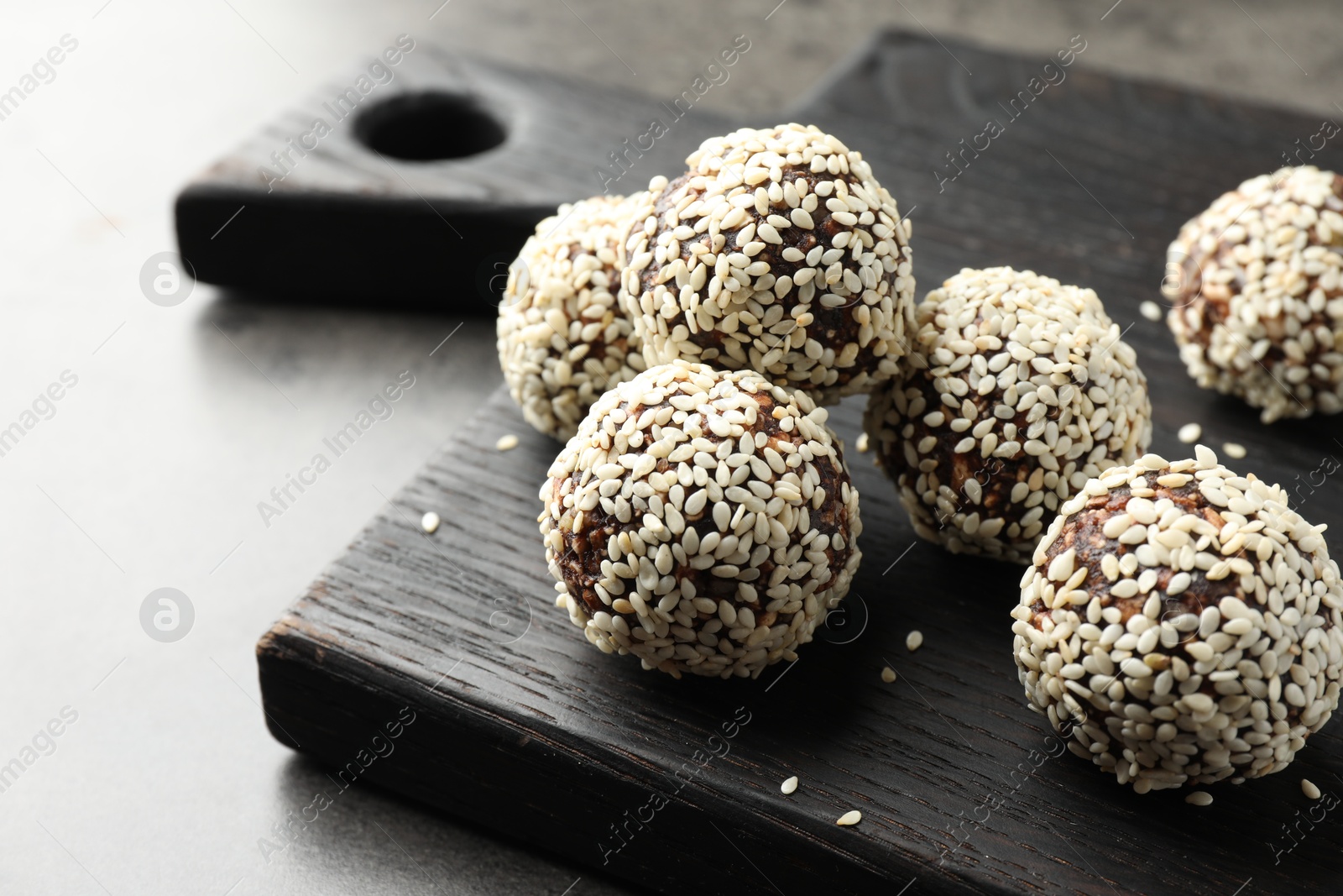 Tasty chocolate candies with nuts and sesame seeds on grey table, closeup Photo of Tasty chocolate candies with nuts and sesame seeds on grey table, closeup