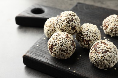 Photo of Tasty chocolate candies with nuts and sesame seeds on grey table, closeup