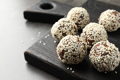 Photo of Tasty chocolate candies with nuts and sesame seeds on grey table, closeup