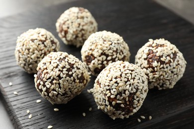 Photo of Tasty chocolate candies with nuts and sesame seeds on table, closeup