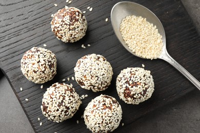 Photo of Tasty chocolate candies with nuts and sesame seeds on grey table, top view
