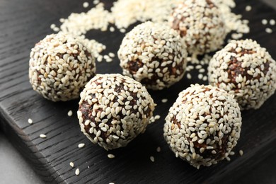 Photo of Tasty chocolate candies with nuts and sesame seeds on table, closeup