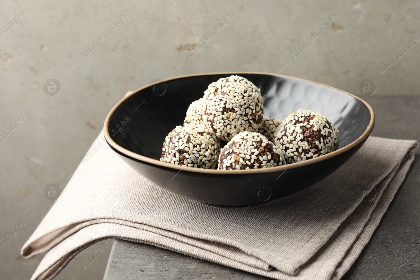 Tasty chocolate candies with nuts and sesame seeds on grey table, closeup Photo of Tasty chocolate candies with nuts and sesame seeds on grey table, closeup