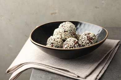 Photo of Tasty chocolate candies with nuts and sesame seeds on grey table, closeup