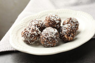 Photo of Tasty chocolate candies with nuts and coconut flakes on grey table, closeup