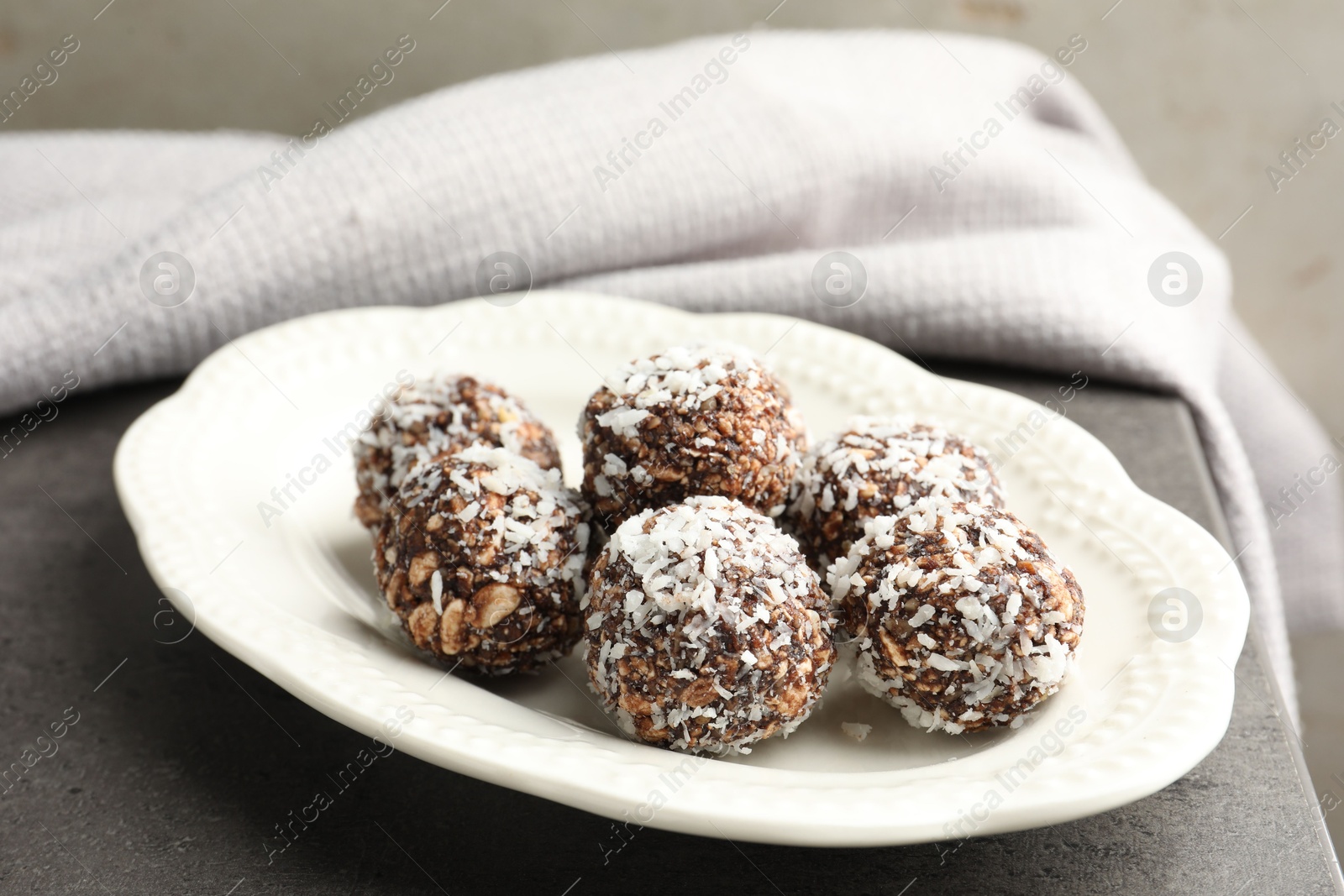 Tasty chocolate candies with nuts and coconut flakes on grey table, closeup Photo of Tasty chocolate candies with nuts and coconut flakes on grey table, closeup