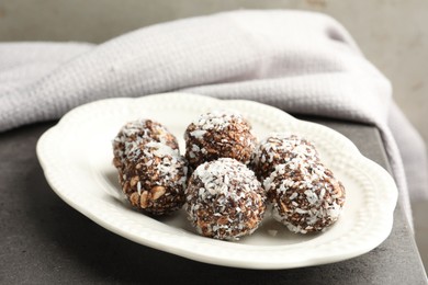 Photo of Tasty chocolate candies with nuts and coconut flakes on grey table, closeup