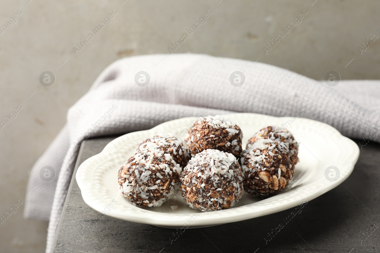 Tasty chocolate candies with nuts and coconut flakes on grey table, closeup Photo of Tasty chocolate candies with nuts and coconut flakes on grey table, closeup