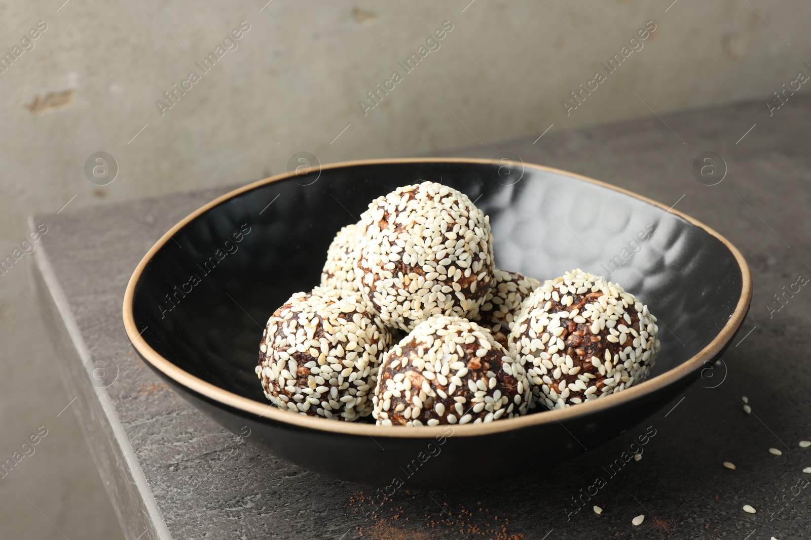 Tasty chocolate candies with nuts and sesame seeds on grey table, closeup Photo of Tasty chocolate candies with nuts and sesame seeds on grey table, closeup