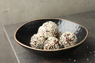 Photo of Tasty chocolate candies with nuts and sesame seeds on grey table, closeup