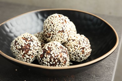 Photo of Tasty chocolate candies with nuts and sesame seeds on grey table, closeup