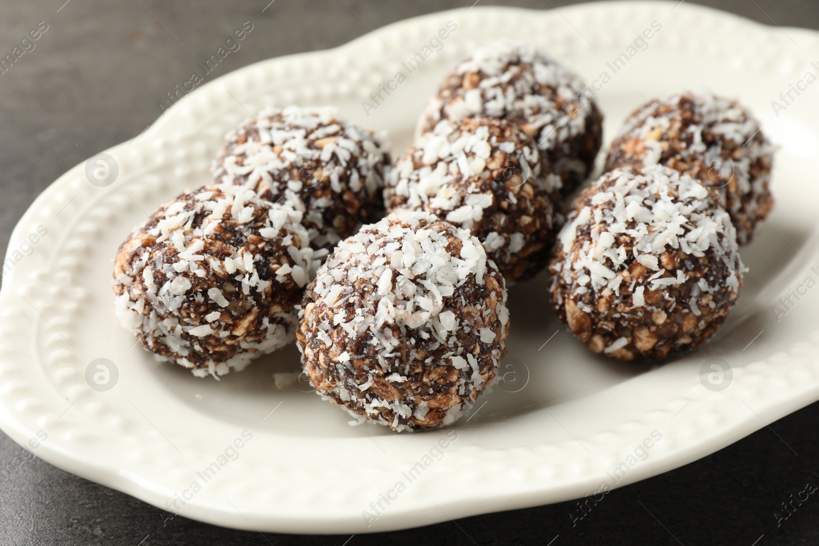 Tasty chocolate candies with nuts and coconut flakes on grey table, closeup Photo of Tasty chocolate candies with nuts and coconut flakes on grey table, closeup