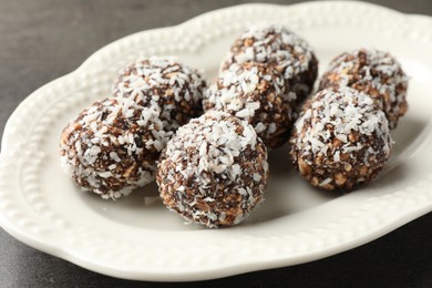 Photo of Tasty chocolate candies with nuts and coconut flakes on grey table, closeup