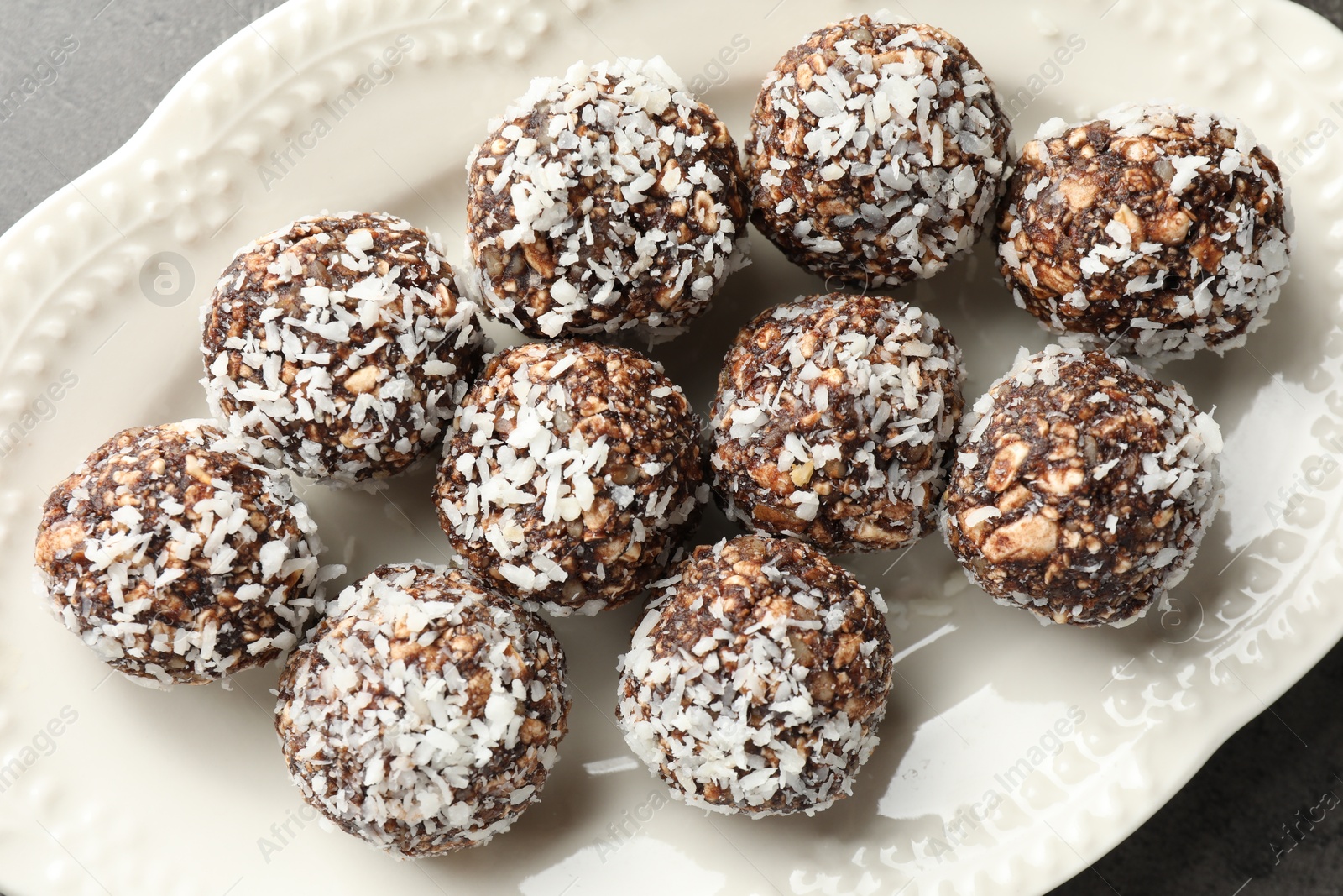 Tasty chocolate candies with nuts and coconut flakes on grey table, top view Photo of Tasty chocolate candies with nuts and coconut flakes on grey table, top view