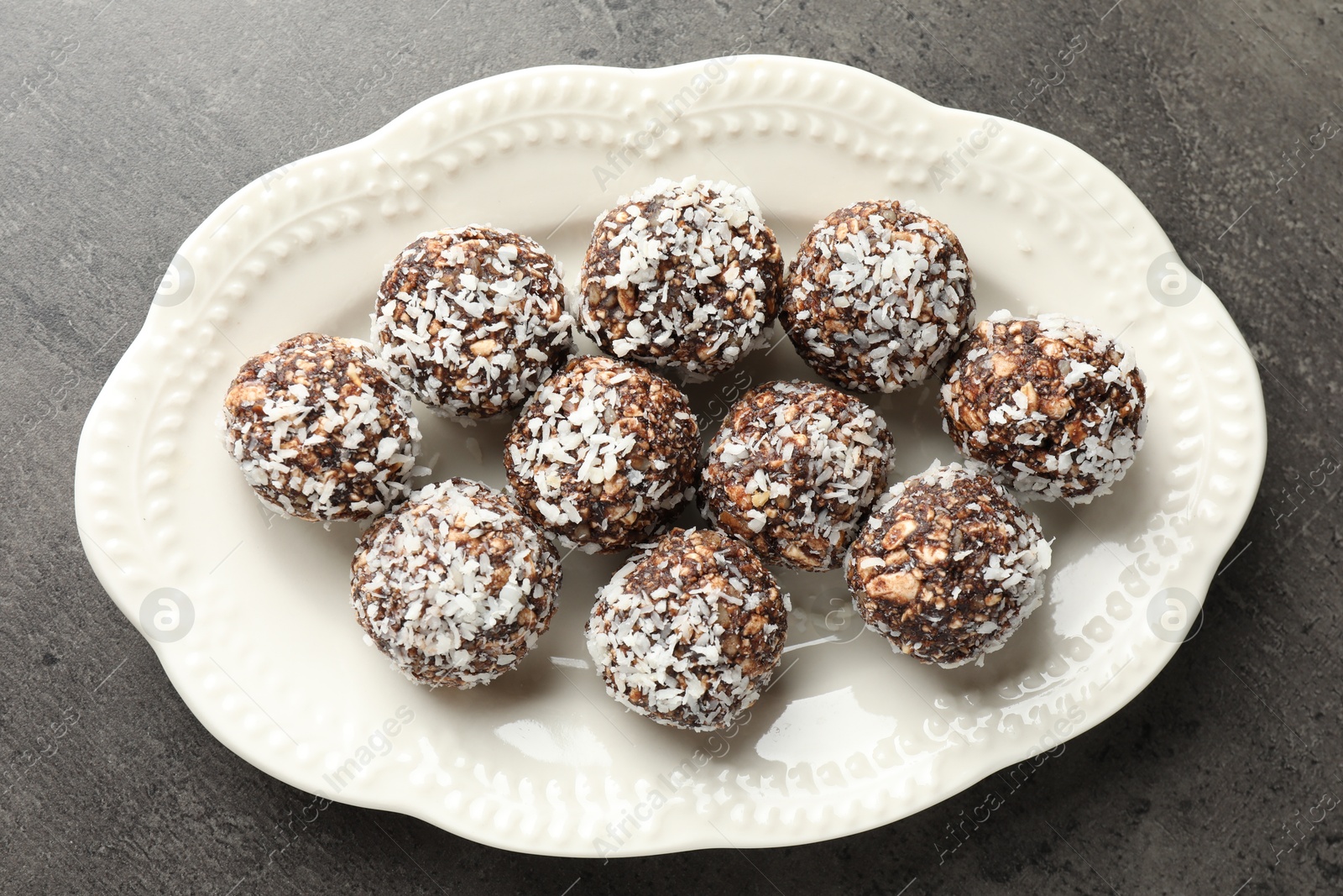 Tasty chocolate candies with nuts and coconut flakes on grey table, top view Photo of Tasty chocolate candies with nuts and coconut flakes on grey table, top view