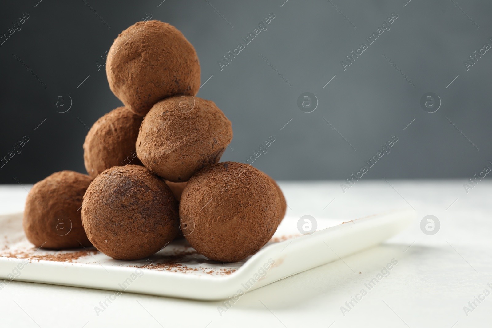 Tasty chocolate candies with cocoa powder on white table, closeup. Space for text Photo of Tasty chocolate candies with cocoa powder on white table, closeup. Space for text