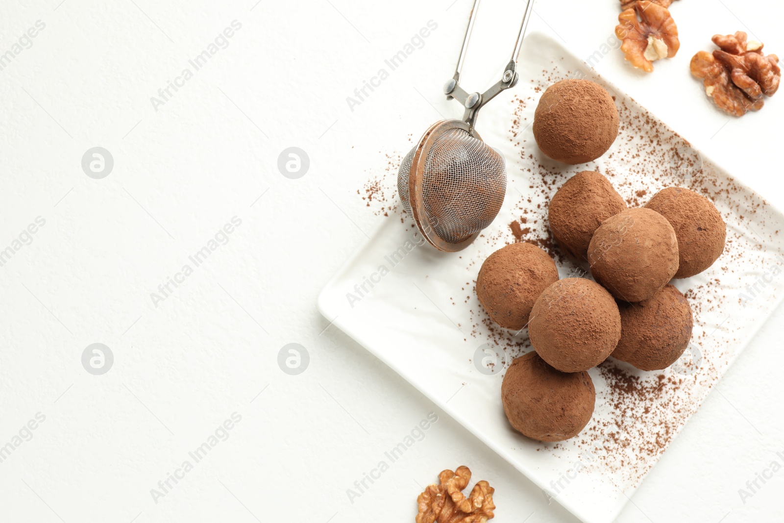 Tasty chocolate candies with cocoa powder and walnuts on white table, flat lay. Space for text Photo of Tasty chocolate candies with cocoa powder and walnuts on white table, flat lay. Space for text