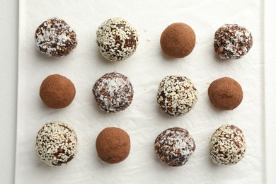 Photo of Tasty chocolate candies with cocoa powder, nuts and sesame seeds on white table, top view