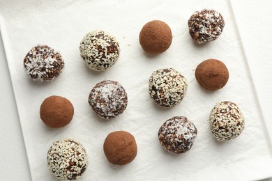 Photo of Tasty chocolate candies with cocoa powder, nuts and sesame seeds on white table, top view