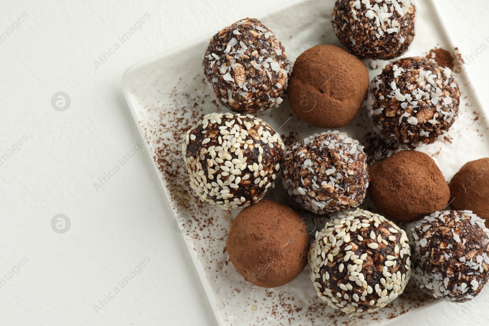 Tasty chocolate candies with cocoa powder, nuts and sesame seeds on white table, top view. Space for text Photo of Tasty chocolate candies with cocoa powder, nuts and sesame seeds on white table, top view. Space for text