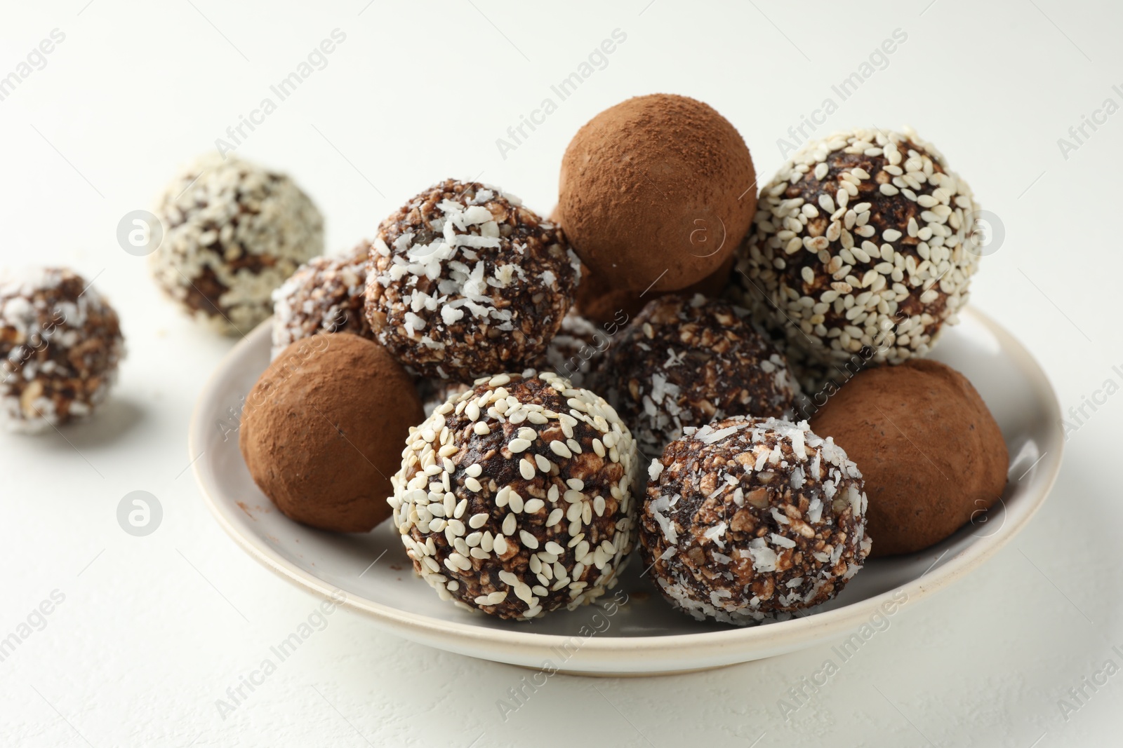 Tasty chocolate candies with cocoa powder, nuts and sesame seeds on white table, closeup Photo of Tasty chocolate candies with cocoa powder, nuts and sesame seeds on white table, closeup