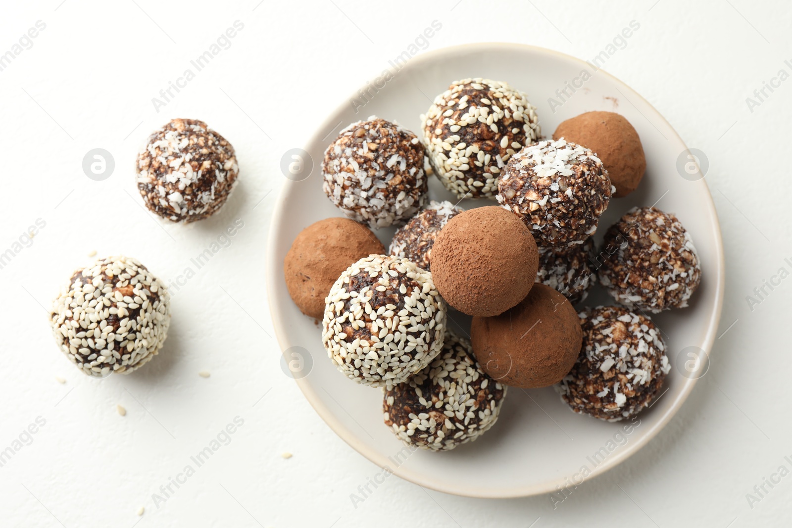 Tasty chocolate candies with cocoa powder, nuts and sesame seeds on white table, top view Photo of Tasty chocolate candies with cocoa powder, nuts and sesame seeds on white table, top view